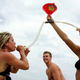 Two college women drinking from beer bong on beach